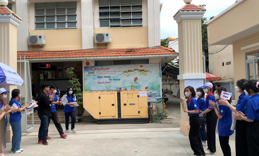 Các tình nguyện viên xếp 2 hàng vỗ tay cổ vũ thí sinh tại điểm thi Trường THPT Giồng Ông Tố.