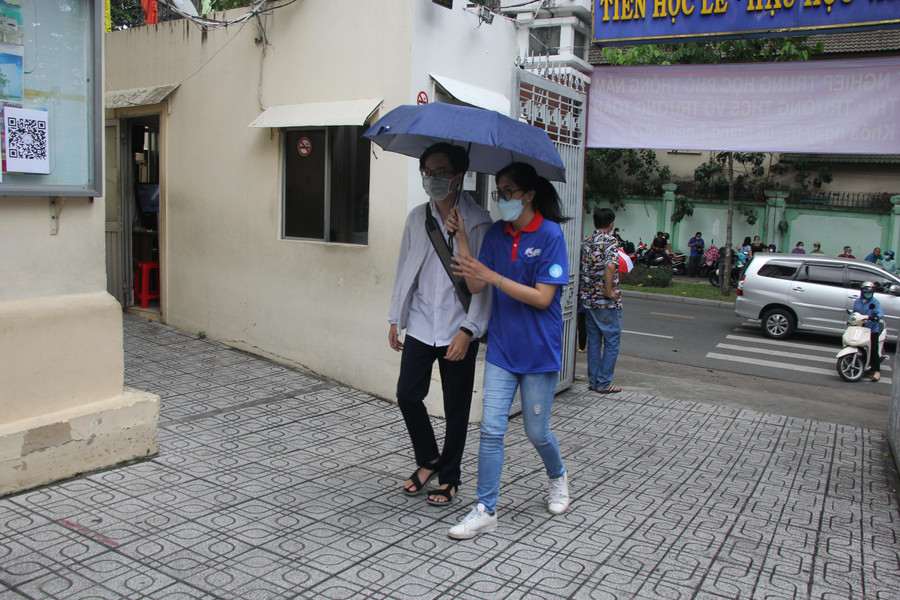 Tình nguyện viên dùng ô che nắng cho thí sinh vào điểm thi Trường THCS Võ Trường Toản.