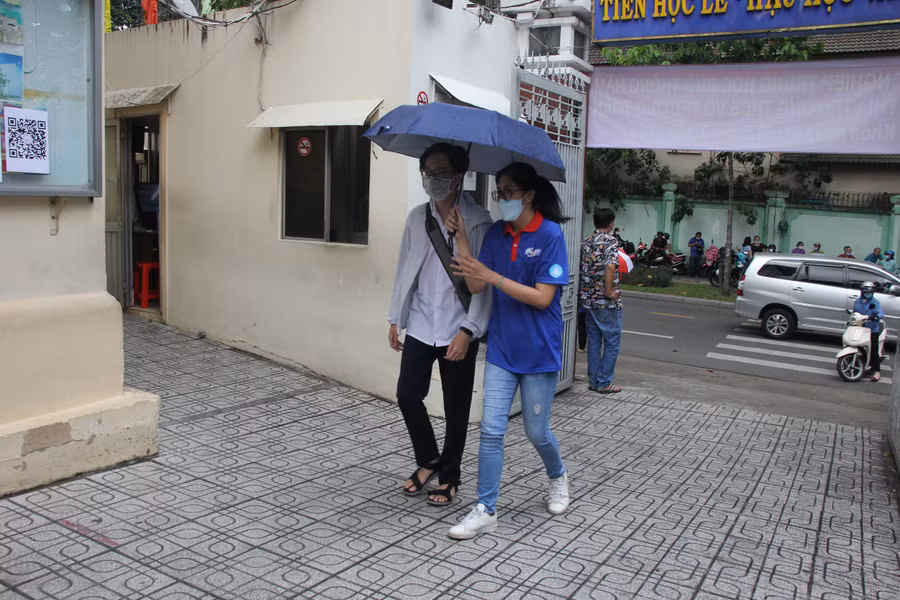 Tình nguyện viên dùng ô che nắng cho thí sinh vào điểm thi Trường THCS Võ Trường Toản.