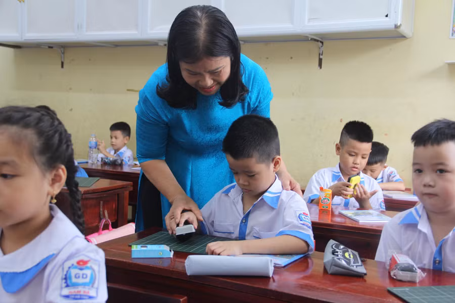 GV hướng dẫn học sinh làm quen với đồ dùng học tập.