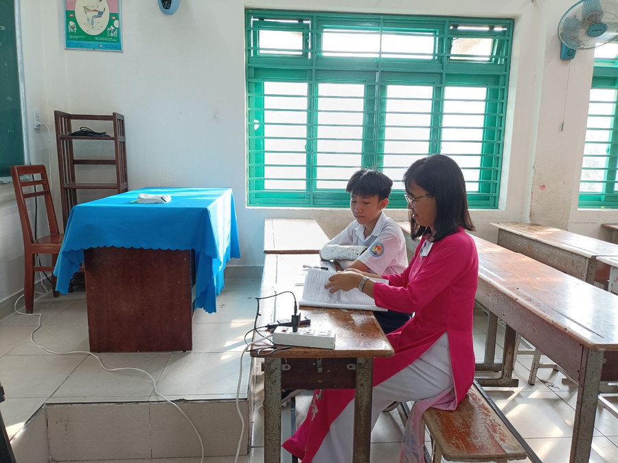 Thí sinh Minh Nguyên tại phòng thi đặc biệt có cán bộ coi thi viết hộ bài dưới sự giám sát của camera và thiết bị ghi âm. Thí sinh Minh Nguyên tại phòng thi đặc biệt có cán bộ coi thi viết hộ bài dưới sự giám sát của camera và thiết bị ghi âm.