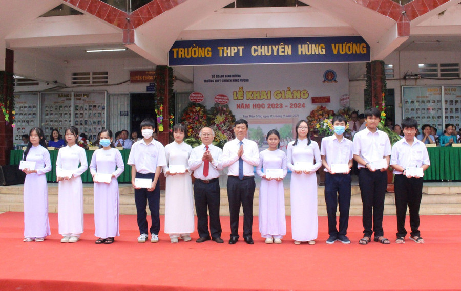 Ông Võ Văn Minh (thứ 6 từ phải qua) và lãnh đạo Hội Khuyến học tỉnh Bình Dương trao học bổng cho các em học sinh có hoàn cảnh khó khăn tại trường THPT Chuyên Hùng Vương.