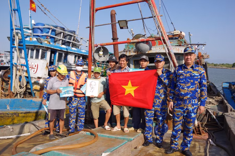 Cán bộ đội tuyên truyền trao tặng cờ Tổ quốc, ảnh Bác Hồ và phát tờ rơi tuyên truyền cho ngư dân.