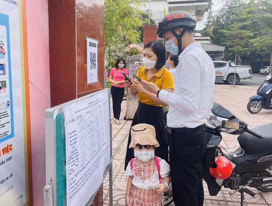 Phụ huynh quét mã QR qua phấn mềm BlueZone để kiểm tra và khai báo y tế trước cổng trường