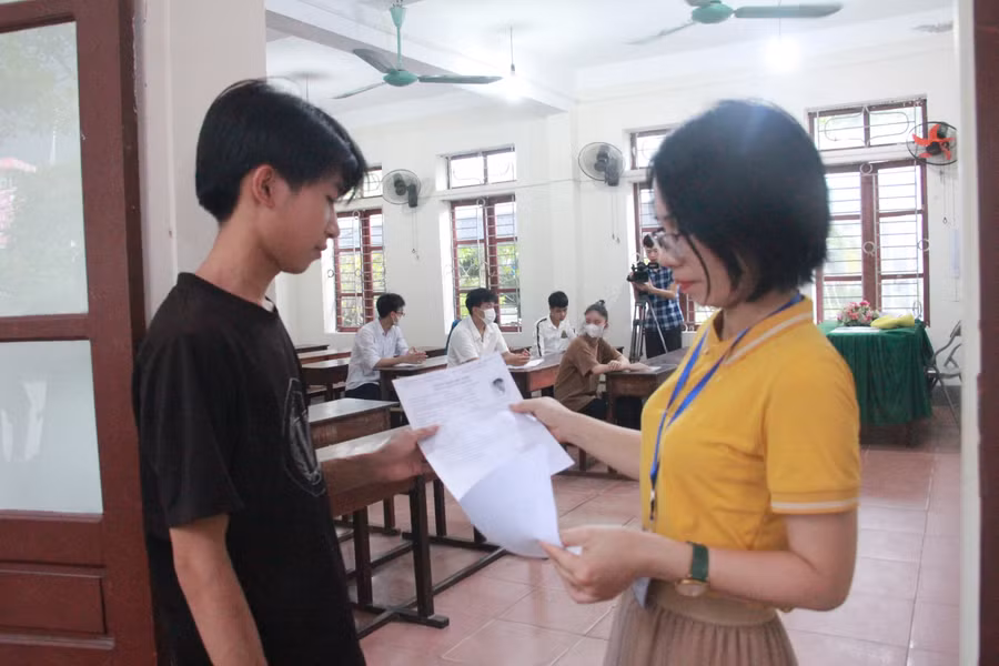 Giám thị kiểm tra thông tin thí sinh trước khi vào phòng thi làm thủ tục.