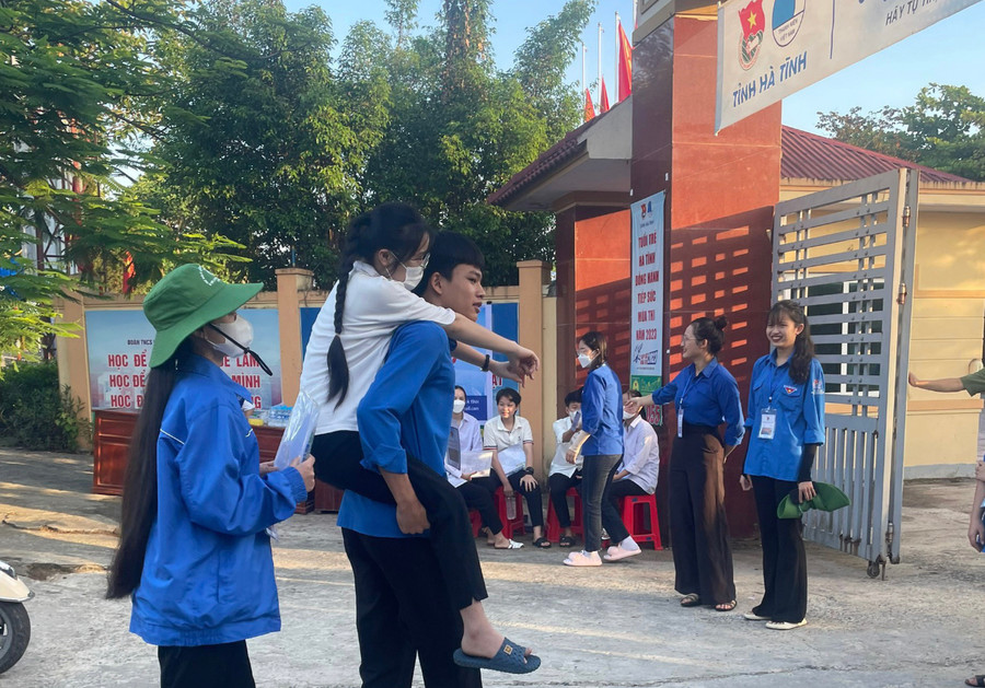 Tình nguyện viên tại điểm thi Trường THPT Cẩm Bình cõng thí sinh bị gãy chân vào phòng thi.