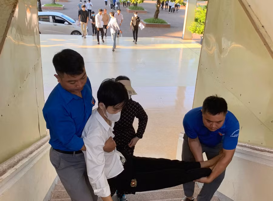 Thí sinh Nguyễn Tấn Tài được lực lượng tình nguyện bế lên phòng thi do bị gãy chân.