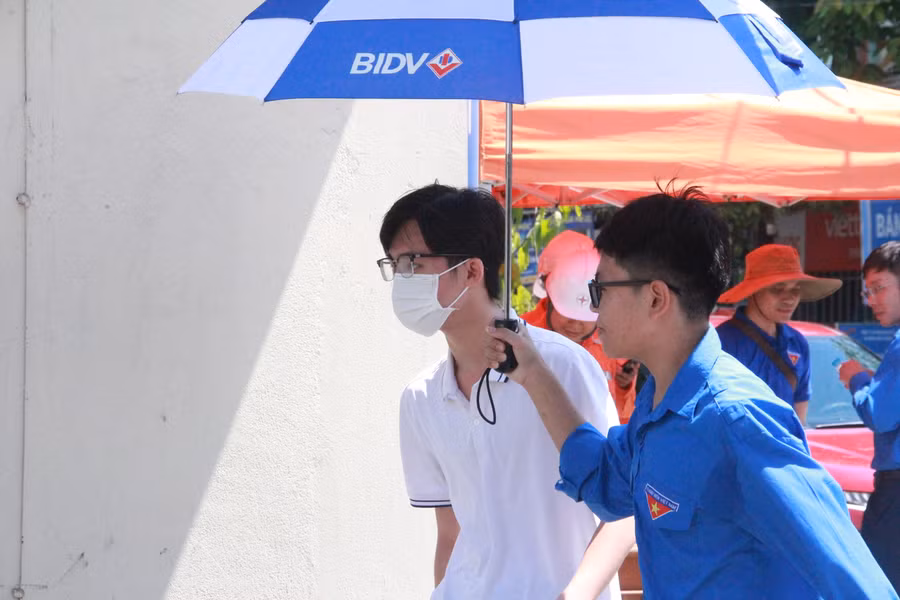 Tình nguyện viên trường THPT Chuyên Hà Tĩnh che ô cho các sĩ tử vào tận phòng thi.