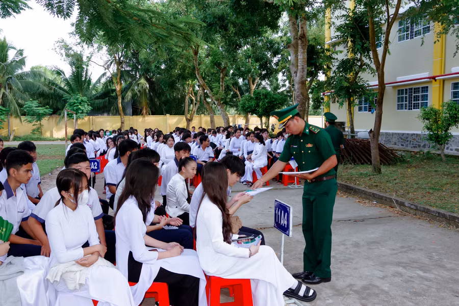 Cán bộ đồn Biên phòng Trung Bình phát tờ rơi tuyên truyền cho các em học sinh.