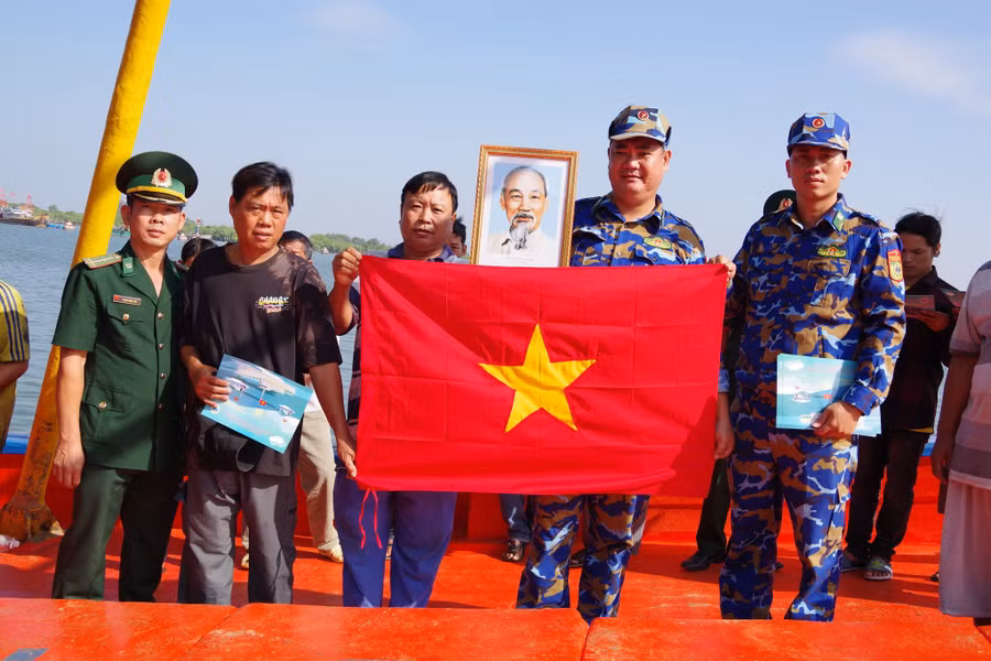 Cán bộ biên phòng tặng cờ Tổ quốc, phát tờ rơi tuyên truyền cho ngư dân.