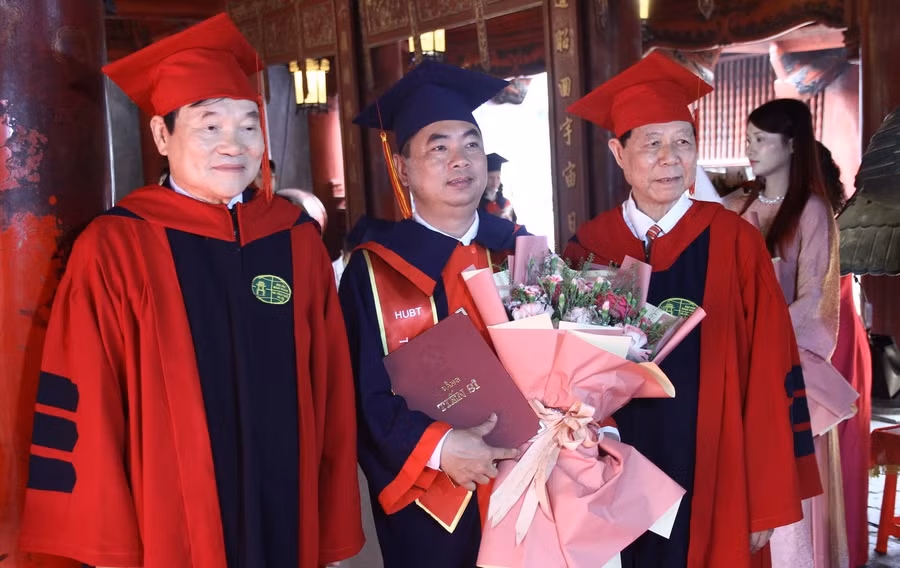 PGS.TS Phạm Dương Châu và PGS, TS Phạm Văn Đăng - Phó Viện trưởng thường trực Viện đào tạo Sau đại học trao bằng và tặng hoa cho tân tiến sĩ.