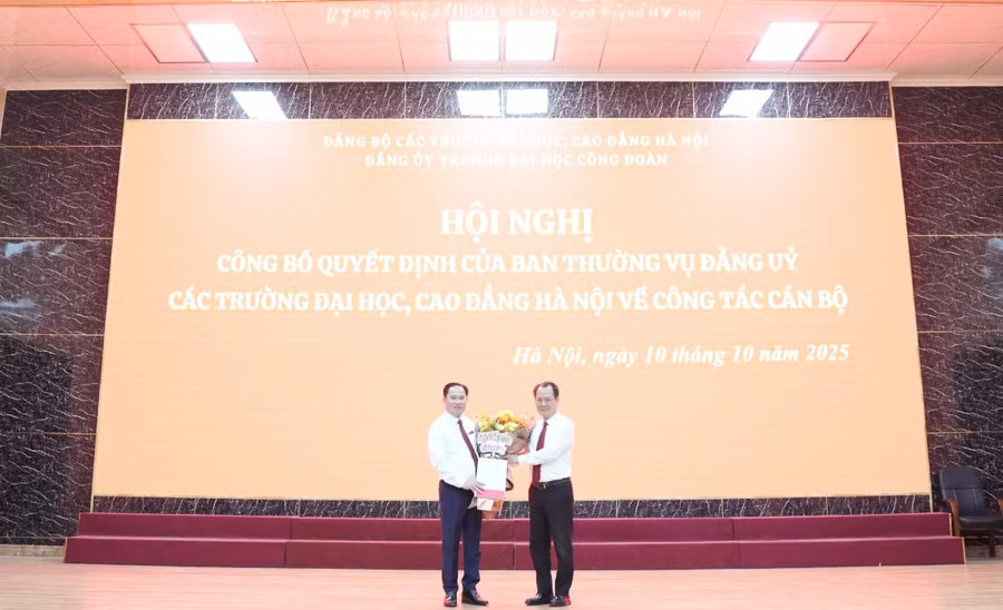 Đồng chí Nguyễn Thanh Sơn - Bí thư Đảng ủy các trường Đại học, Cao đẳng Hà Nội (bên phải) trao quyết định và tặng hoa cho đồng chí Lê Mạnh Hùng.