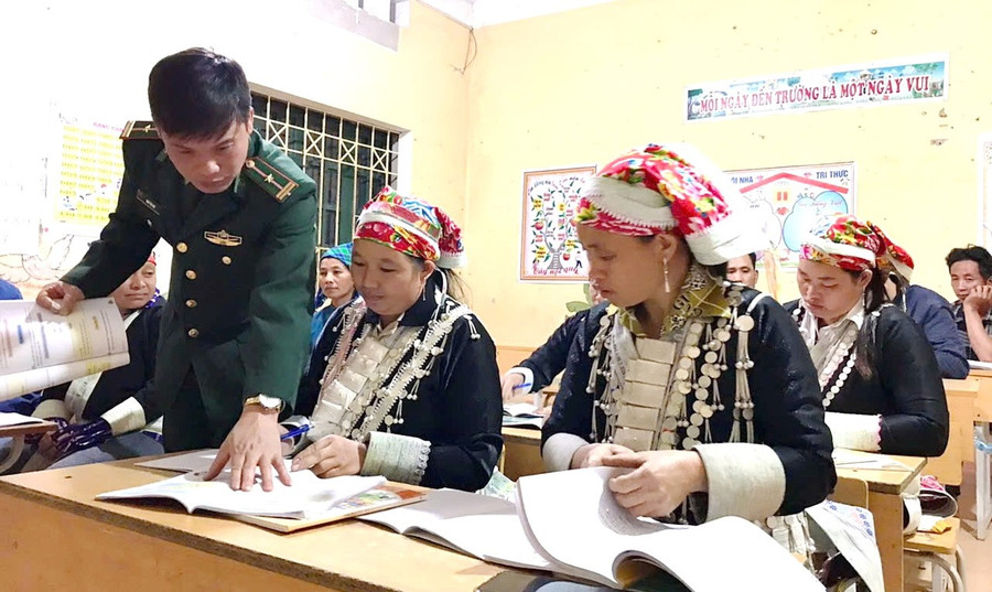 Trung tá Đinh Thái Đạt hướng dẫn học viên tại lớp học xóa mù chữ. 