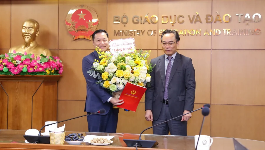 Thứ trưởng Bộ GD&ĐT Hoàng Minh Sơn (bên phải) trao Quyết định và tặng hoa chúc mừng tân Vụ trưởng Vụ Giáo dục đại học Nguyễn Tiến Thảo.