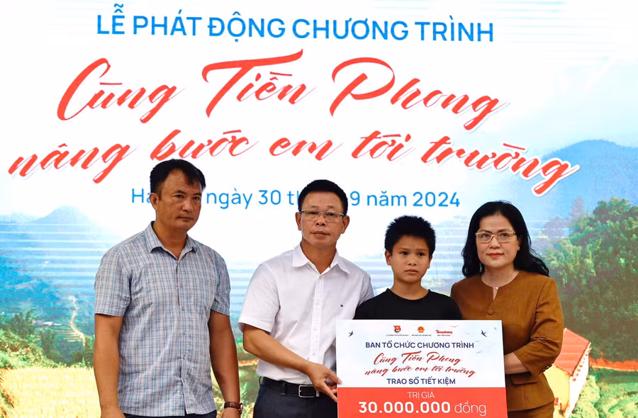 Thứ trưởng Nguyễn Thị Kim Chi và nhà báo Phùng Công Sưởng trao sổ tiết kiệm cho học sinh làng Nủ.