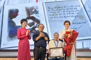 Nhà báo Vũ Việt Trang, Tổng giám đốc TTXVN và nhà thơ Trần Đăng Khoa, Phó Chủ tịch Hội Nhà văn Việt Nam, Chủ tịch Hội đồng giám khảo trao Giải Hiệp sĩ Dế Mèn cho nhạc sĩ Phạm Tuyên. Ảnh: Huy Thông.