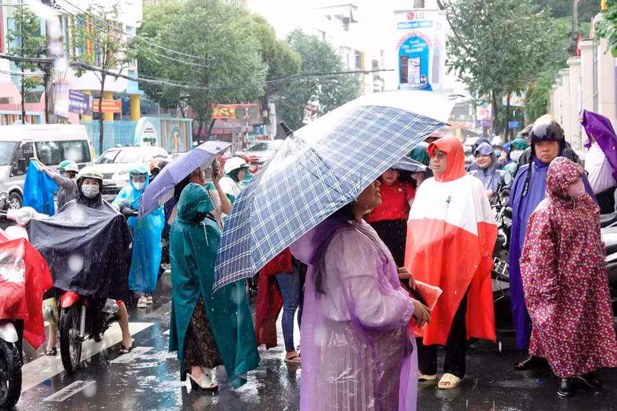 Phụ huynh đội mưa chờ đón thí sinh dự thi môn Ngữ văn vào sáng 26/6.