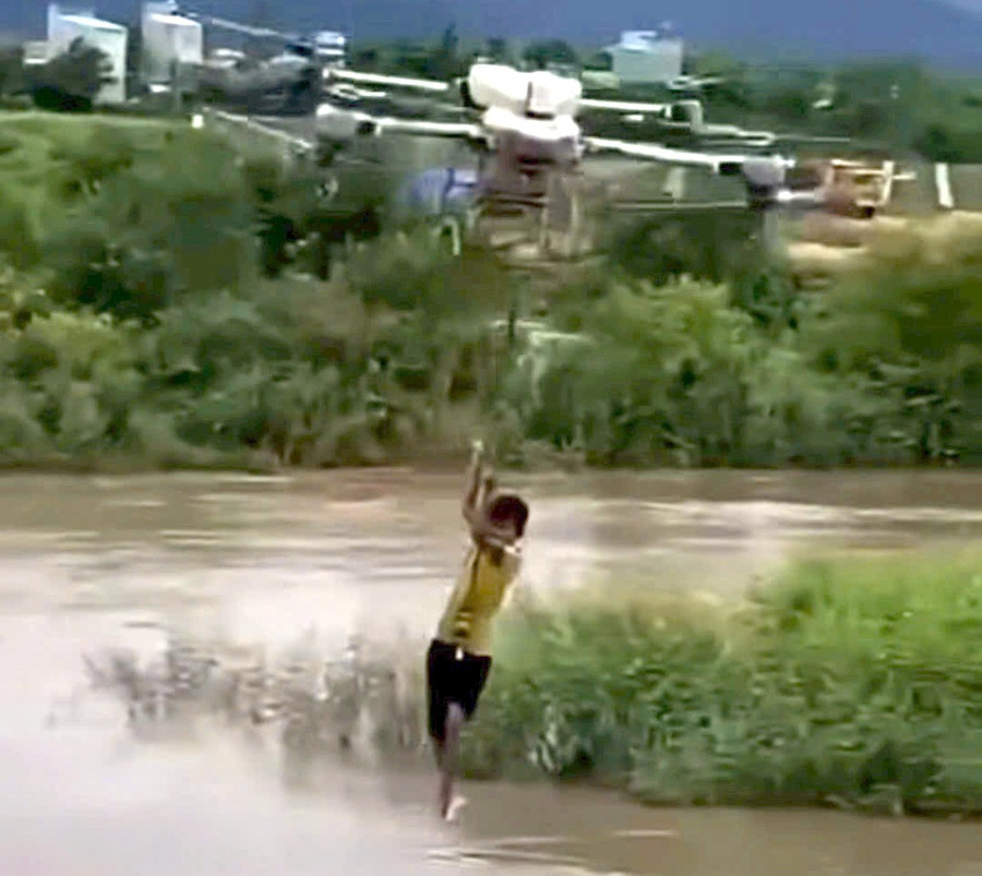 Máy bay không người lái đưa cháu bé bị mắc kẹt giữa dòng nước chảy siết vào bờ. Ảnh cắt từ clip.
