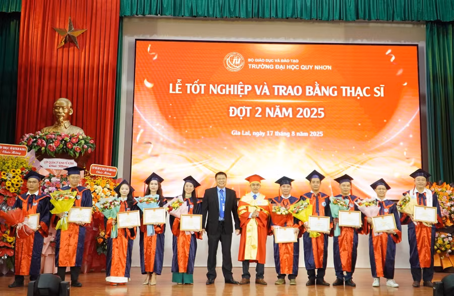 PGS.TS Nguyễn Quang Ngoạn, Chủ tịch Hội đồng Trường Đại học Quy Nhơn (áo đen) và PGS.TS Đoàn Đức Tùng tặng giấy khen cho 10 tân thạc sĩ xuất sắc.
