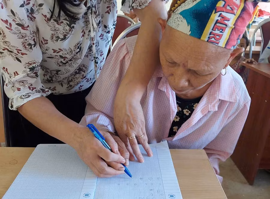 Cô giáo cầm tay luyện từng nét chữ cho học viên lớp xóa mù.