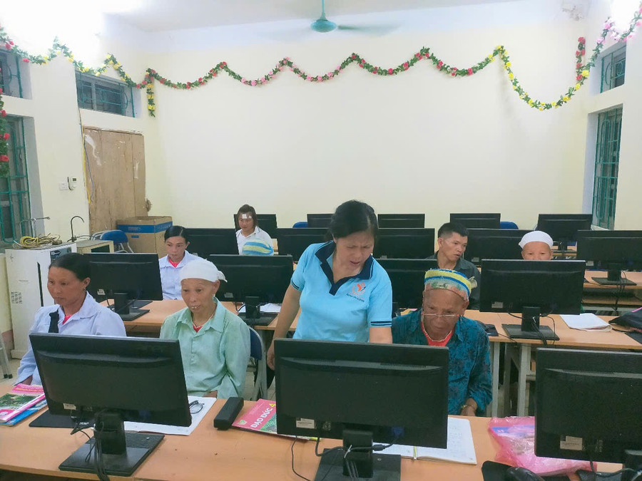 Cụ Phùng Mùi Coi (ngoài cùng bên phải), 68 tuổi, xóm Lũng Quáng, xã Huy Giáp (Cao Bằng) được cô giáo hướng dẫn học tập cùng máy tính.