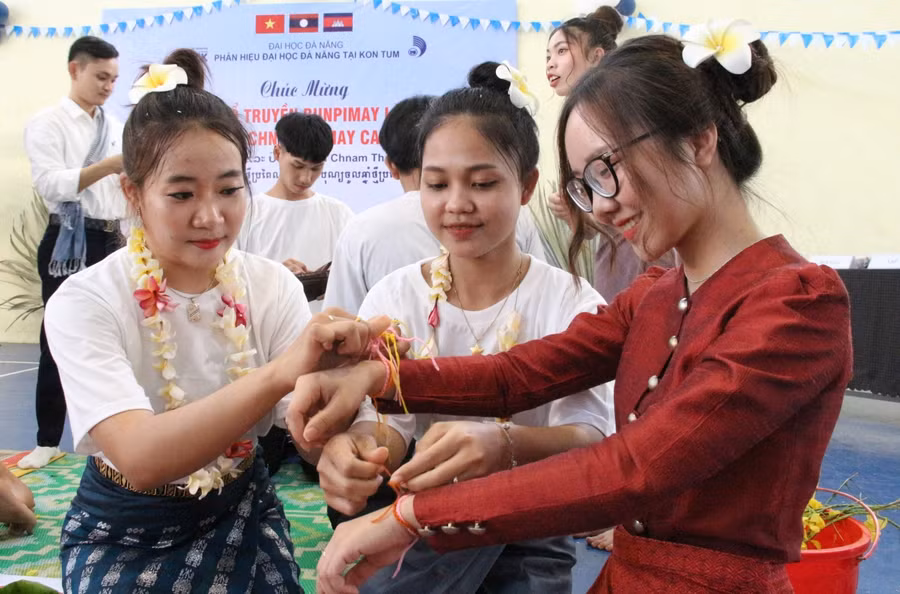 Lưu học sinh Lào buộc chỉ cổ tay cho nhau cầu chúc điều may mắn, tốt lành.
