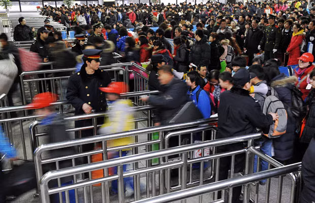 Khoảng 150 triệu người Trung Quốc chen chân về quê ăn Tết ảnh 11 Passengers move through barriers to board a train at a railway station in Beijing, taking the journey home for the Lunar New Year