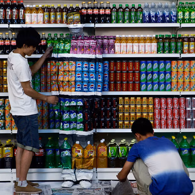 Chinese artist Liu Bolin is painted to blend into rows of drinks in his artwork entitled 