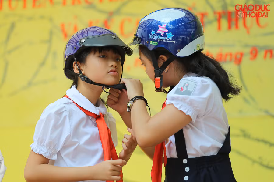 Học sinh tiểu học thực hành đội mũ bảo hiểm đúng cách cho mình và cho bạn khác.