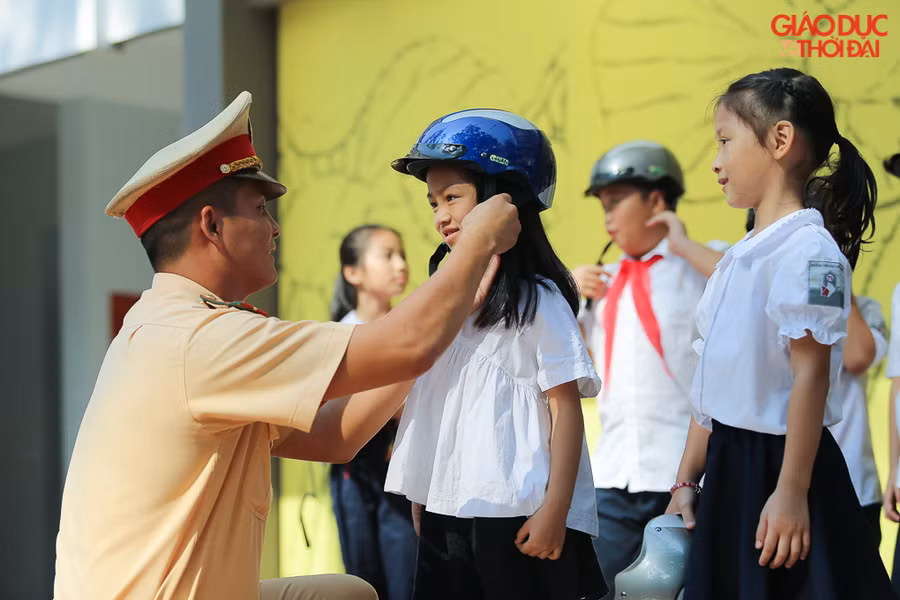 Học sinh được các đồng chí CSGT hướng dẫn đội mũ bảo hiểm đúng cách.