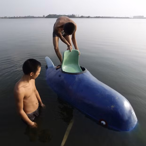 An asisstant working for Zhang Wuyi, a local farmer who is interested in scientific inventions, puts a chair into his homemade miniature submarine Shuguang Hao before Zhang drives it for a safety test at Moshui Lake in Wuhan, capital of central China’s Hubei province