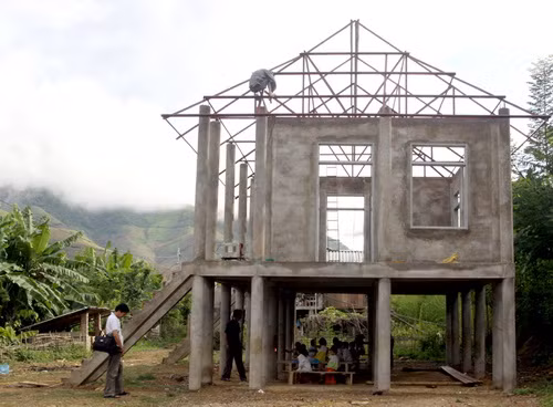 Dưới cô trò học, còn trên thì thợ sắt đang thi công phần mái