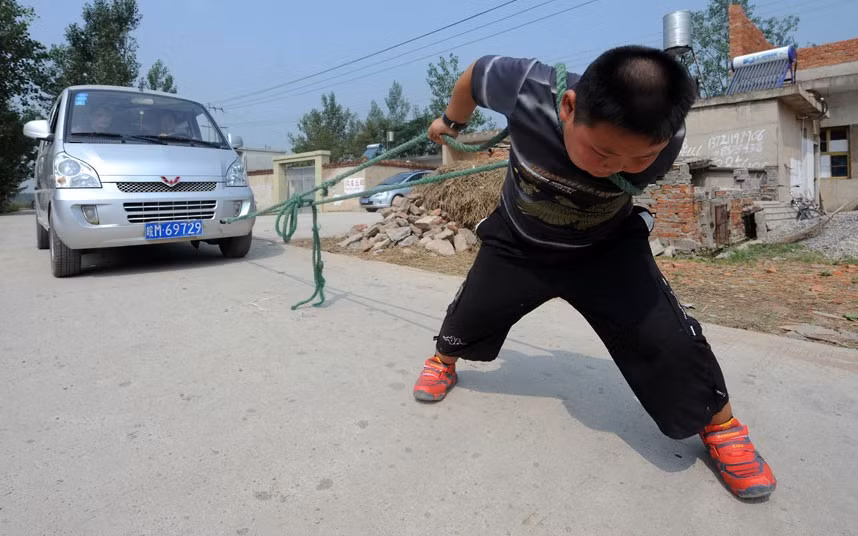 Những hình ảnh ấn tượng trong tuần ảnh 5 Seven-year-old Yang Jinlong pulls a van with eight adults aboard in Chuzhou, China