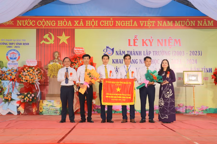 TS Lê Thị Hương, Giám đốc Sở GD&ĐT Quảng Trị trao Cờ thi đua của UBND tỉnh cho Trường THPT Vĩnh Định.