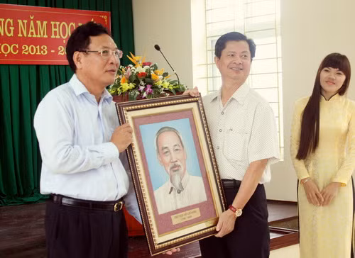 Hiệu trưởng Trường THPT chuyên Lam Sơn (giữa) trân trọng đón nhận ảnh Bác Hồ từ Bộ trưởng Phạm Vũ Luận tặng cho nhà trường.