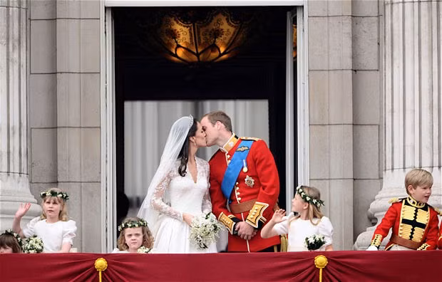 Prince William and his wife Kate, Duchess of Cambridge kiss on the balcony in Buckingham Palace after their wedding service