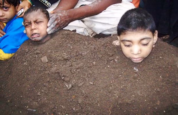 Những hiện tượng kỳ lạ trong năm 2009 ảnh 23 Paralysed children in Gulbarga, India, lie partially buried in piles of manure during the total solar eclipse, in the belief that the eclipse will cure them