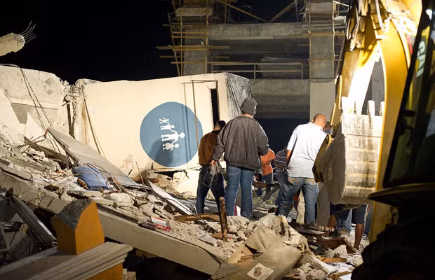 People search for survivors amongst the ruins of the children’s hospital in Port-au-Prince