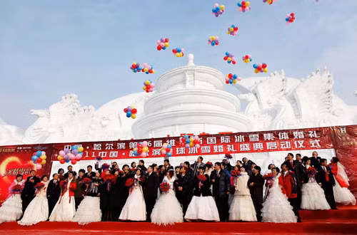 Couples participate in a group wedding ceremony in front of a snow sculpture of Beijing’s Temple of Heaven in Harbin, China on January 6, 2010. The wedding was organized by the city government and 28 couples participated in the ceremony, which was attended by local officials.