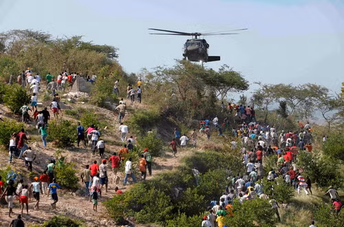 Người dân chạy về phía một máy bay trực thăng của Mỹ khi nó thả những chai nước xuống People run toward a U.S. helicopter as it makes a water drop near a country club used as a forward operating base for the U.S. 82nd Airborne Division in Port-au-Prince, Haiti, Saturday, Jan. 16, 2010. Relief groups and officials are focused on moving aid flowing into Haiti to survivors of the powerful earthquake that hit the country on Tuesday