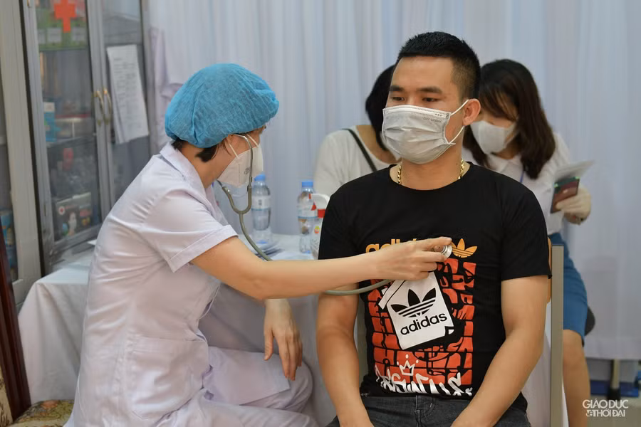 Sau khi khai y tế, người dân sẽ được khám sáng lọc trước khi tiêm.