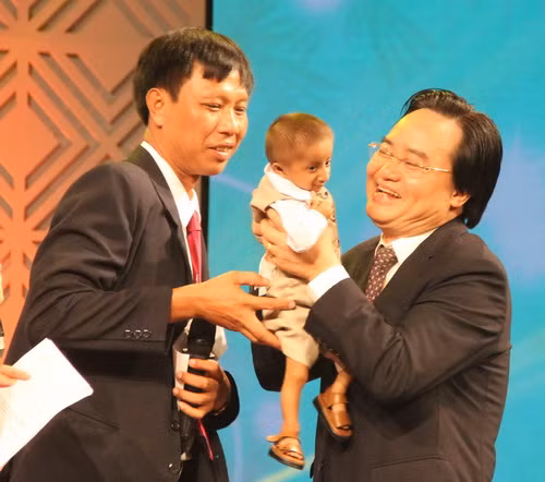 Bộ trưởng Phùng Xuân Nhạ bế em Đinh Văn K"Rể vào lòng và hẹn một ngày sẽ gặp lại hai thầy trò tại Trường Tiểu học Dân tộc bán trú Sơn Ba