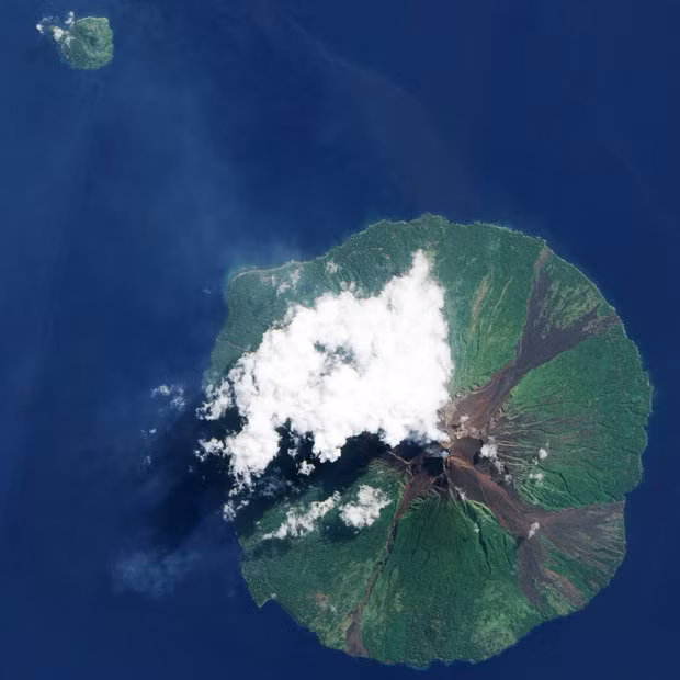 Papua New Guinea’s Manam Volcano releases a thin, faint plume, as clouds cluster at the volcano’s summit