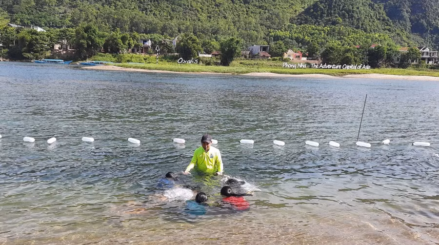 Các em được dạy bơi ở trên sông, xung quanh được căng dây gắn phao.