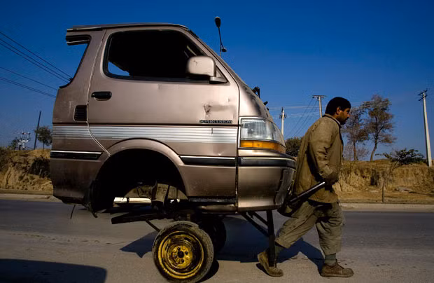 Những hình ảnh ấn tượng trong tuần ảnh 11 A labourer transports the front portion of a van on a road in Rawalpindi, Pakistan