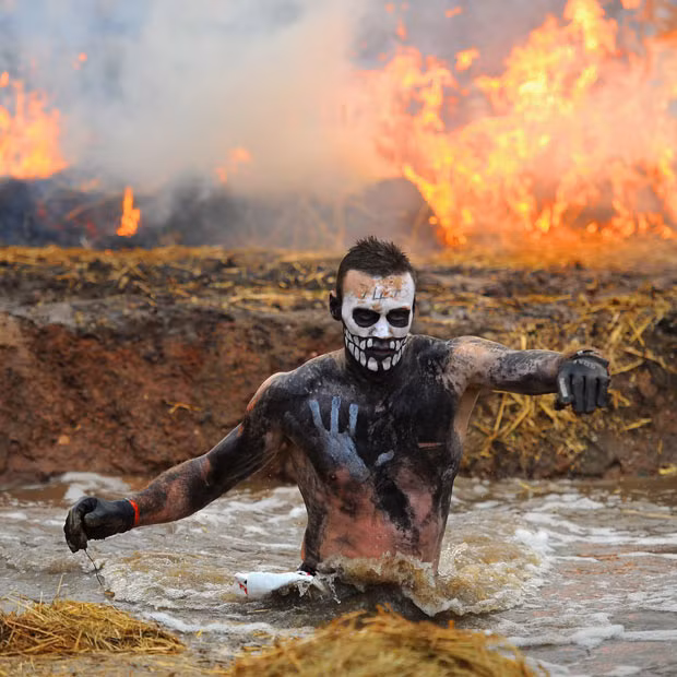 A competitor runs through water during the Tough Guy Challenge endurance race in Telford