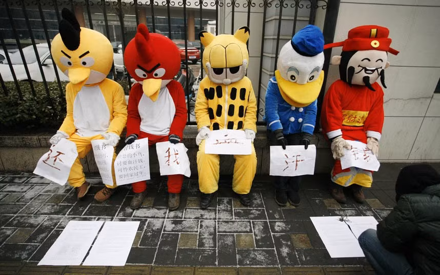 Migrant workers dressed up as Angry Birds, Garfield, Donald Duck and the Chinese God of Wealth (R) during a sit-in protest to demand their salaries outside the China National Radio headquarters in Beijing