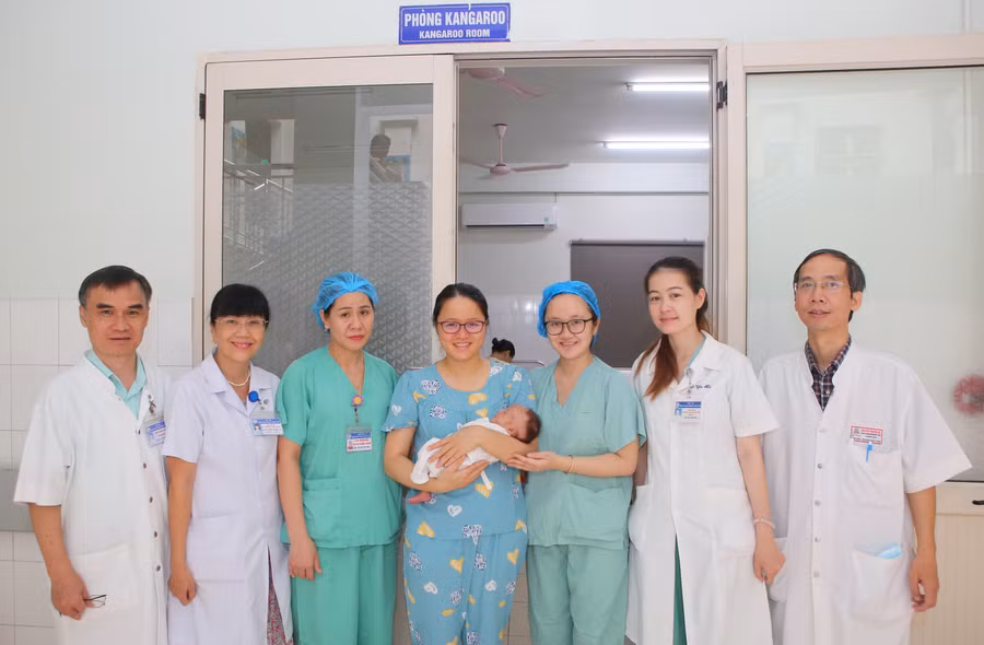 Mẹ và cháu bé sơ sinh bị bệnh xoắn nghẹt ruột non hiếm gặp (giữa) chụp ảnh cùng các y bác sĩ Bệnh viện Trung ương Huế ngày ra viện. (Ảnh: T.H.)