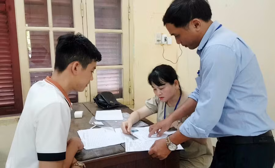 Một thí sinh dò lại thông tin trên phiếu dự thi với danh sách tại phòng thi ở điểm thi Trường THPT Hai Bà Trưng, TP Huế (Ảnh: Đại Dương).