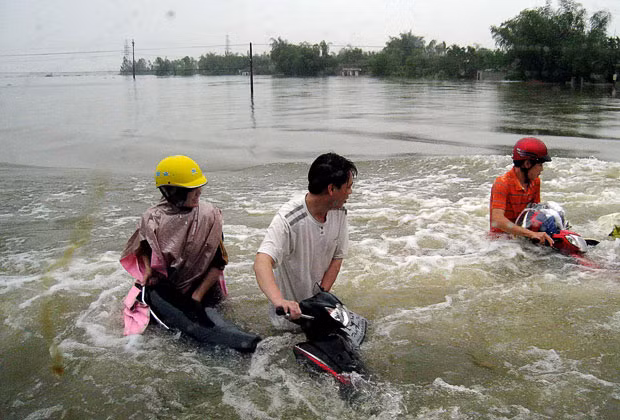 Lụt lội ở Philippines, Thái Lan và Việt Nam trước sức mạnh của Megi ảnh 7 People walk their motorcycles on a flooded section of the national highway Number One in Cam Xuyen district, Ha Tinh province, Vietnam
